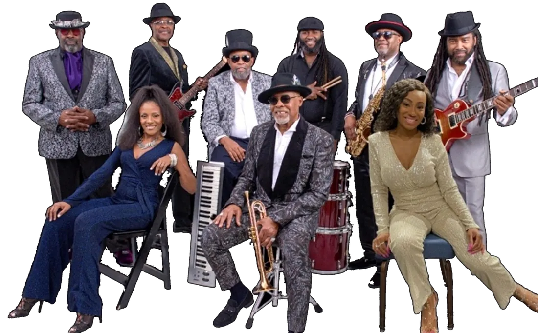 The nine members of The SOS Band in sharp suits and hats, with guitars, saxophone, trumpet, keys and drums.